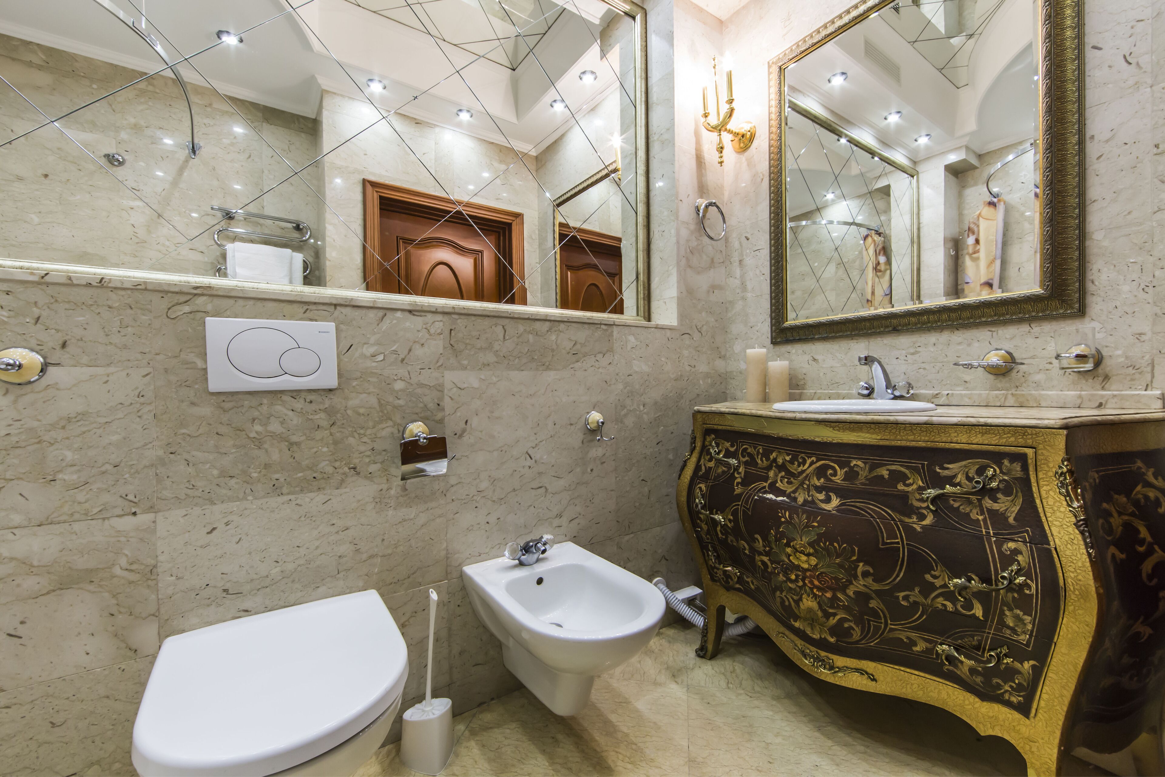 A bathroom with a bidet, toilet, and a sink with a gold-accented vanity.