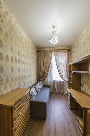 A room with a wooden dresser, a bench with pillows, a chandelier, and patterned wallpaper. - Magnificent Apartment at Luteranska (Kyiv)