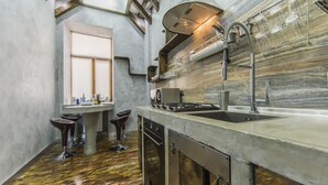 Een moderne keuken met een inbouwoven, een RVS-gootsteen en een raam met zonwering.