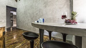 Een moderne eetruimte met een ronde tafel, twee zwarte stoelen, een glas rode wijn, een ananas en een bord met druiven.