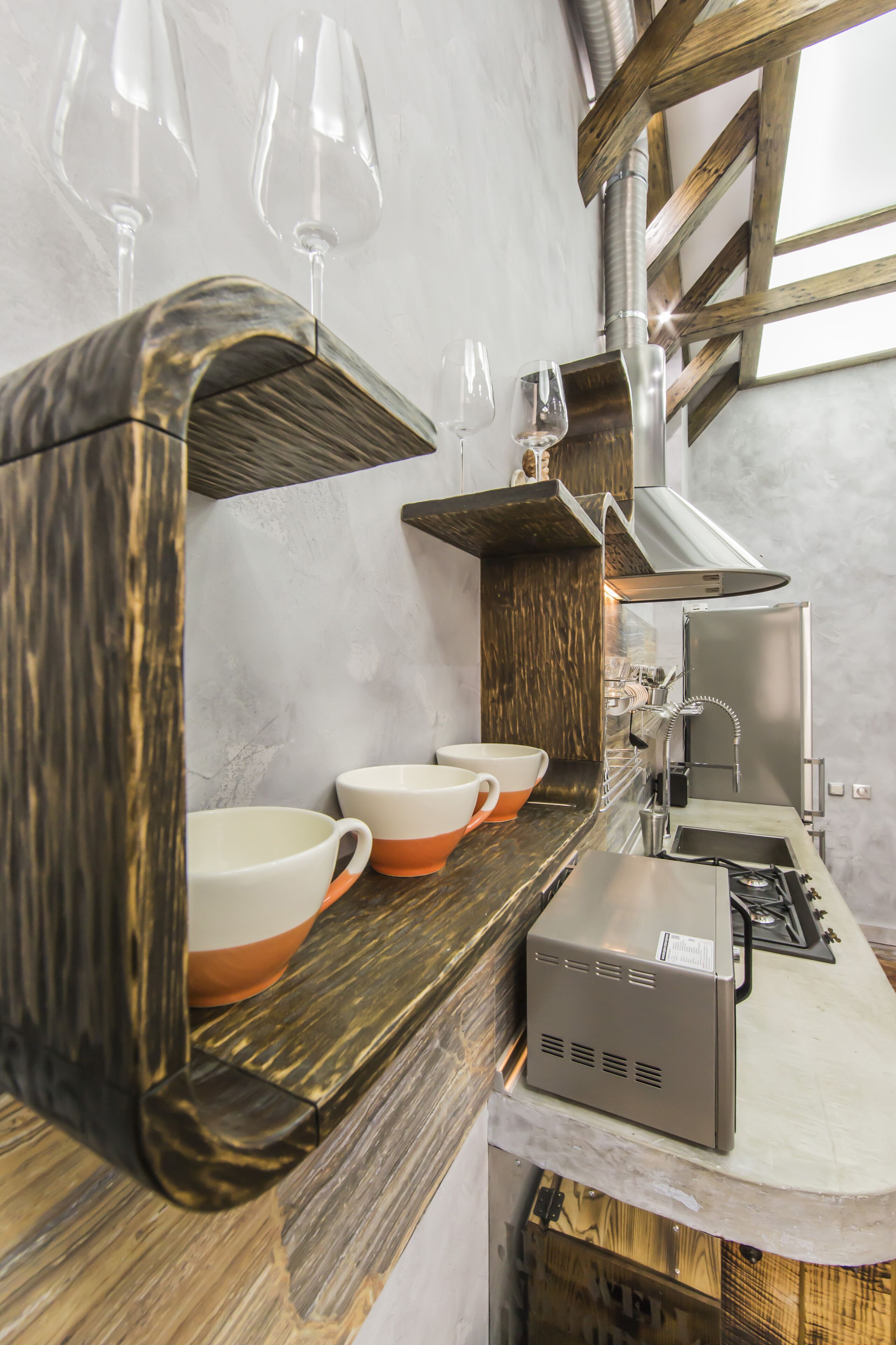 A modern kitchen with a wooden countertop, a built-in stove, and a wine glass rack.
