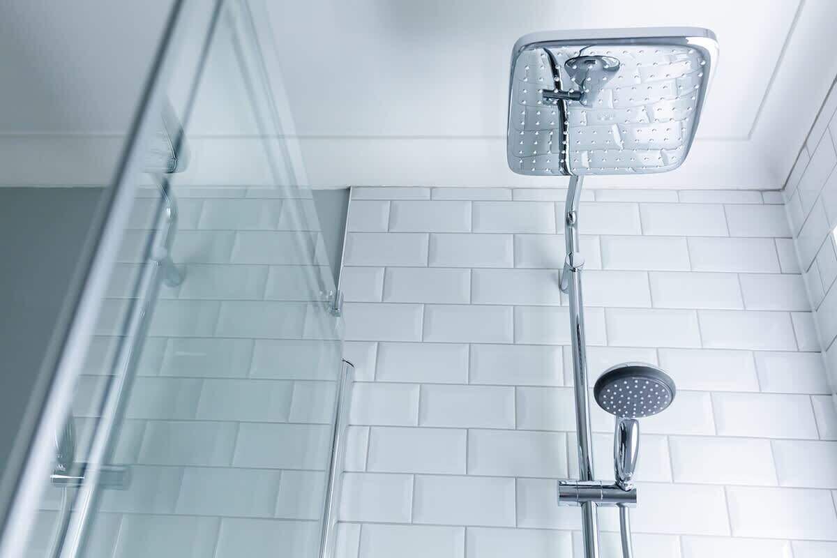 Une douche équipée d’un pommeau de douche à main et d’un pommeau de douche fixe fixé au mur.