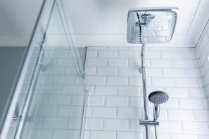 A shower with a handheld showerhead and a fixed showerhead mounted on the wall.