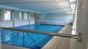 Ein überdachter Pool mit freiem Blick auf das Pool-Areal, inklusive der Poolkante, einer Metall-Sicherheitsreling und Fliesenböden.