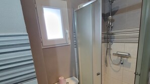 A bathroom with a toilet, a shower, and a window.