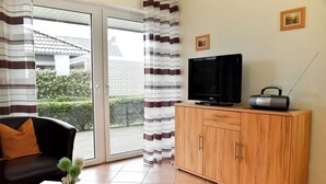 A living room with a sofa, a television, a radio, and a cabinet. - Rubin apartment 2 - Quiet vacation apartment near the Döser sandy beach (Cuxhaven)