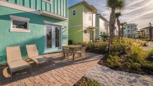 A row of colorful houses with a patio area featuring two chairs and a table.