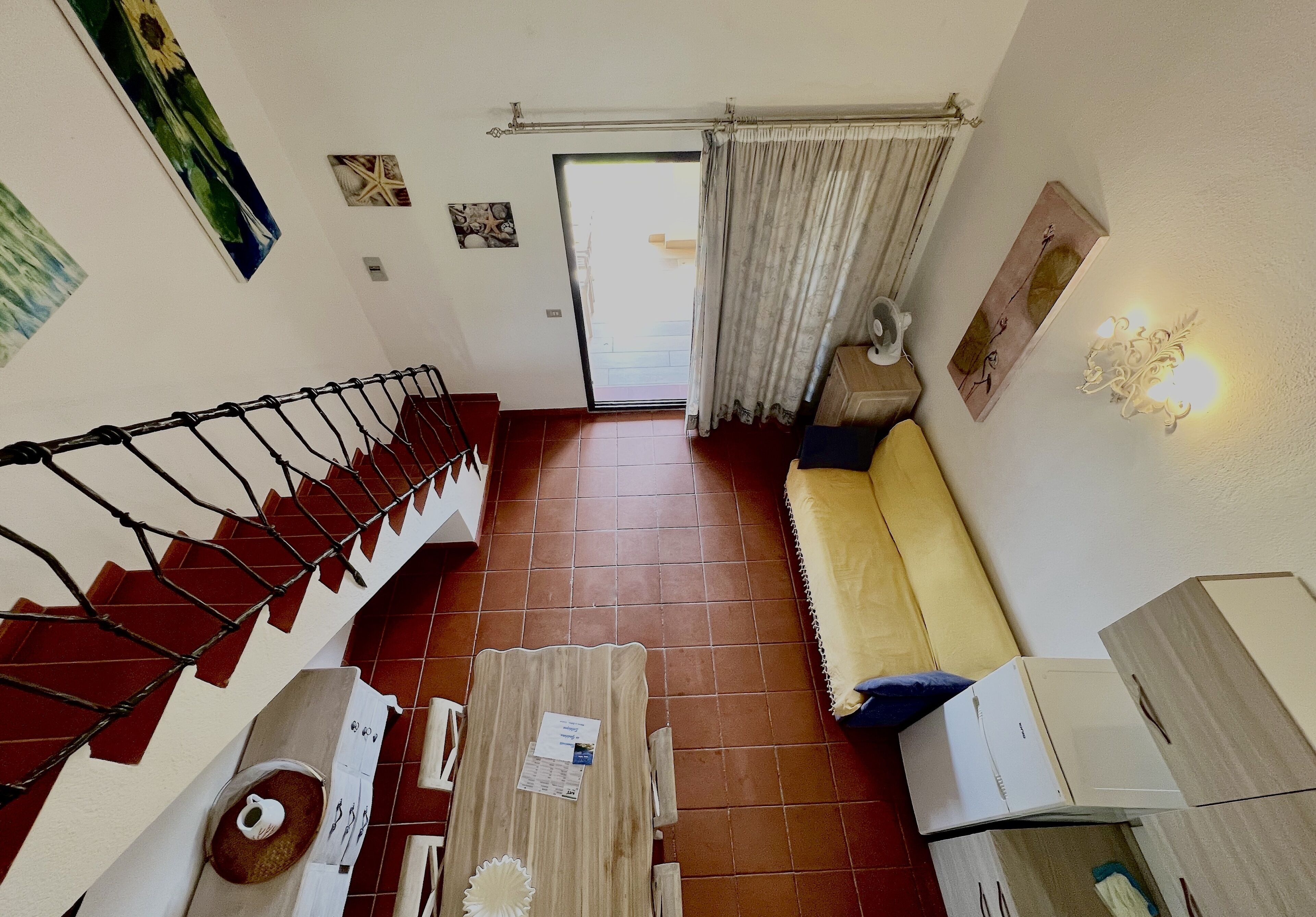 A living room with a staircase, a sofa, a coffee table, and a door leading outside.