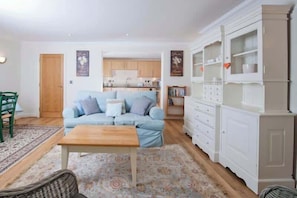 A living room with a sofa, a wooden coffee table, a white cabinet, and a patterned rug.