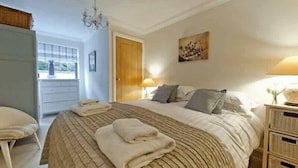 Une chambre à coucher avec un grand lit, des tables de chevet, une chaise et une porte donnant sur un espace extérieur.