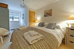 A bedroom with a large bed, bedside tables, a chair, and a door leading to an outdoor area.