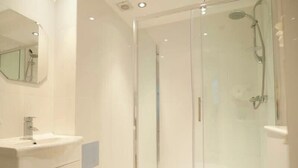 Une salle de bain moderne avec une douche à parois de verre, un lavabo et un miroir.