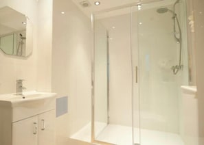 A modern bathroom with a glass-enclosed shower, a sink, and a mirror.