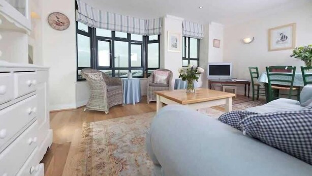 Un salon comprenant un canapé, une table basse, un téléviseur et un coin repas avec des chaises et une table.