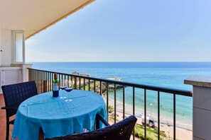 Un balcón con mesa y sillas, con vista a la playa y al mar.