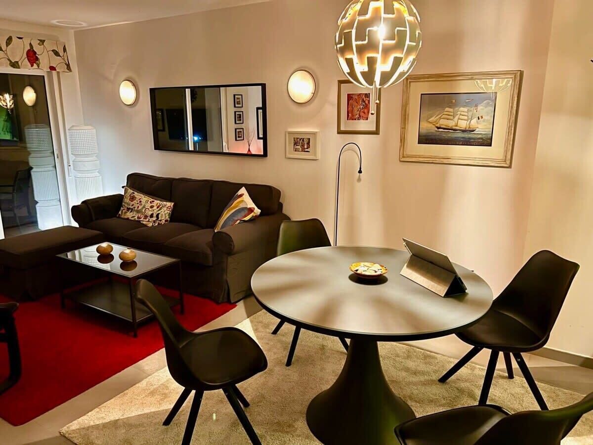 A modern living room with a sofa, coffee table, round dining table, and chairs.