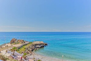 A coastal area with a rocky outcrop, a paved walkway, and a clear view of the sea. - Arce 2 (Nerja)