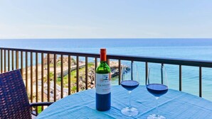 Una mesa con una botella de vino Isla Negra y dos copas en un balcón con vistas al mar.