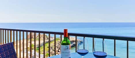 Une table avec une bouteille de vin Isla Negra et deux verres, sur un balcon donnant sur la mer.