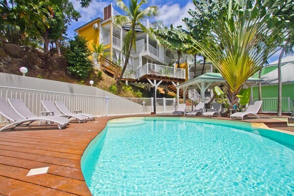 A pool area with lounge chairs and a wooden deck.