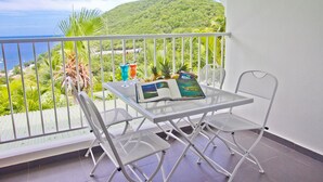 Un balcon avec une table et des chaises, un livre et une boisson.