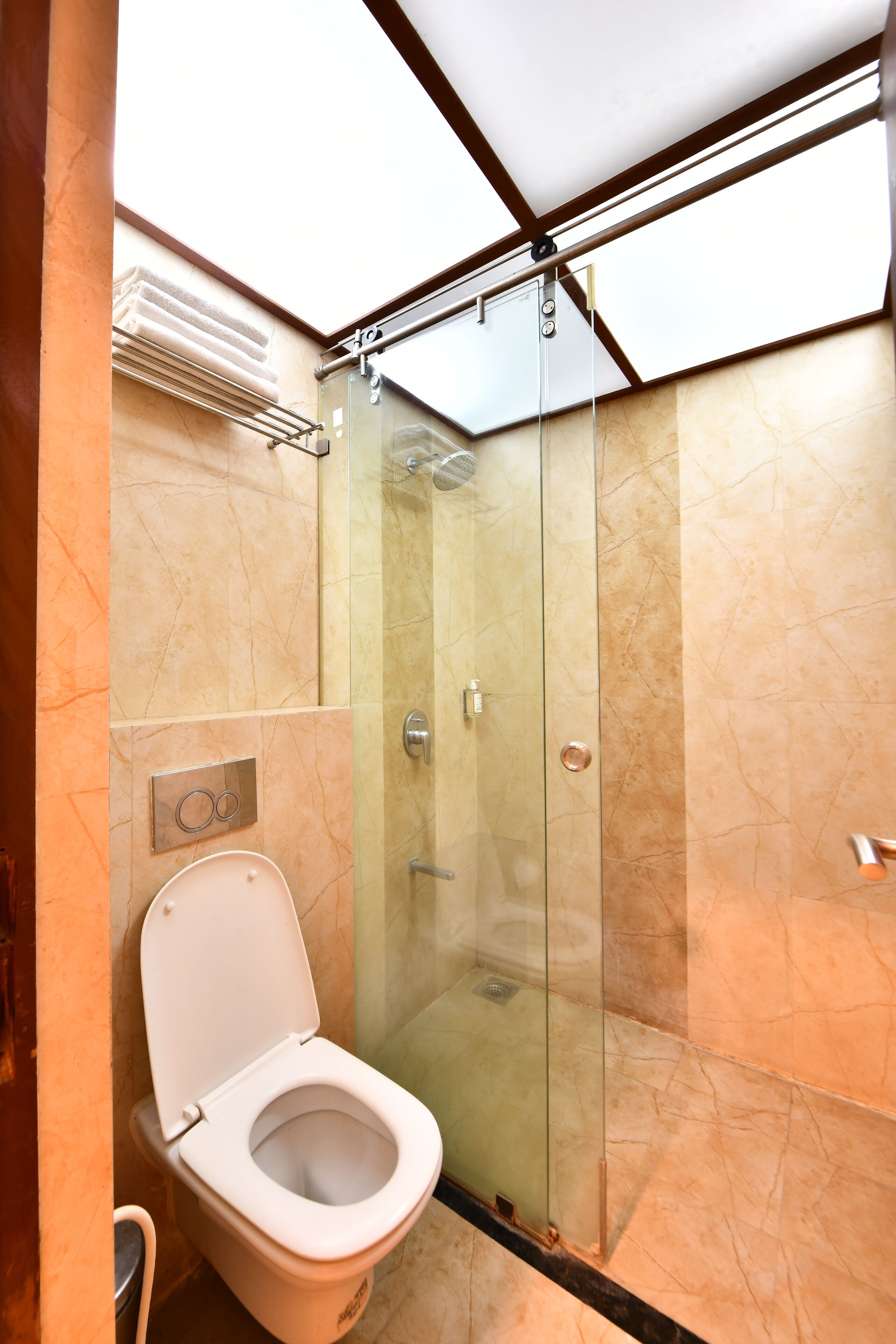 Un baño moderno con ducha de vidrio, inodoro y perchero para toallas.
