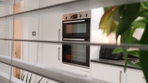 Une cuisine moderne dotée d’un four encastré et d’une horloge numérique affichant 20 h 10.