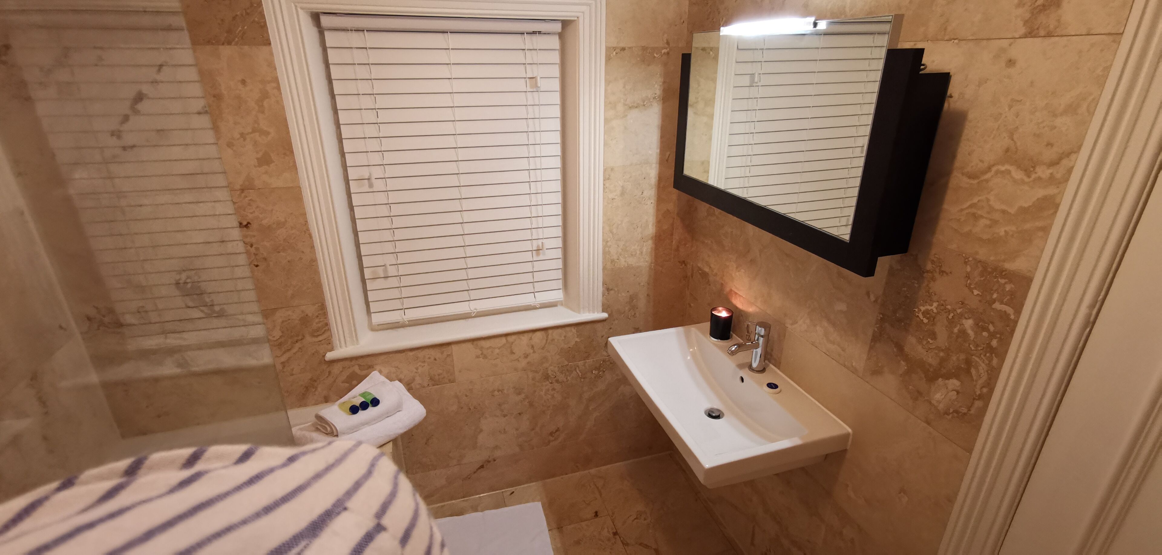 A bathroom with a white sink, a mirror, and a window with blinds.