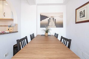 A conference room with a long wooden table, black chairs, a potted plant, and a framed picture on the wall.