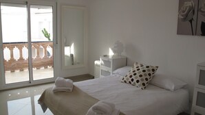 A hotel room with a bed, a nightstand, a lamp, a window with a view of a building and a cactus, and an air conditioning unit. - Hernan Cortes (Nerja)