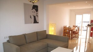 A living room with a sofa, a coffee table, and a dining area with chairs and a table. - Hernan Cortes (Nerja)