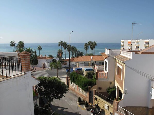 A coastal residential area with buildings, a street, and a view of the sea.