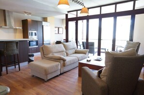 A modern living room with a sofa, armchairs, a coffee table, and a kitchen area with an oven. - Carabeo 1-30 (Nerja)