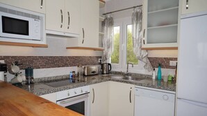 A compact kitchen with a microwave, toaster, kettle, and a sink. - Paraiso Blanco (Nerja)