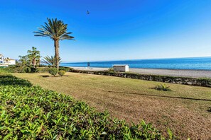A coastal landscape with a palm tree, a small building, and a clear blue sky. - Jardines del Mar (Torrox)