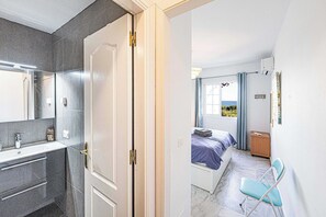 A bedroom with a bed, a chair, a bedside table, and a window with curtains. - Jardines del Mar (Torrox)