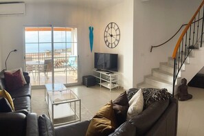 A living room with a sofa, coffee table, TV, and a staircase.