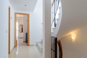 A modern interior with a staircase, a hallway, and a door leading to another room.