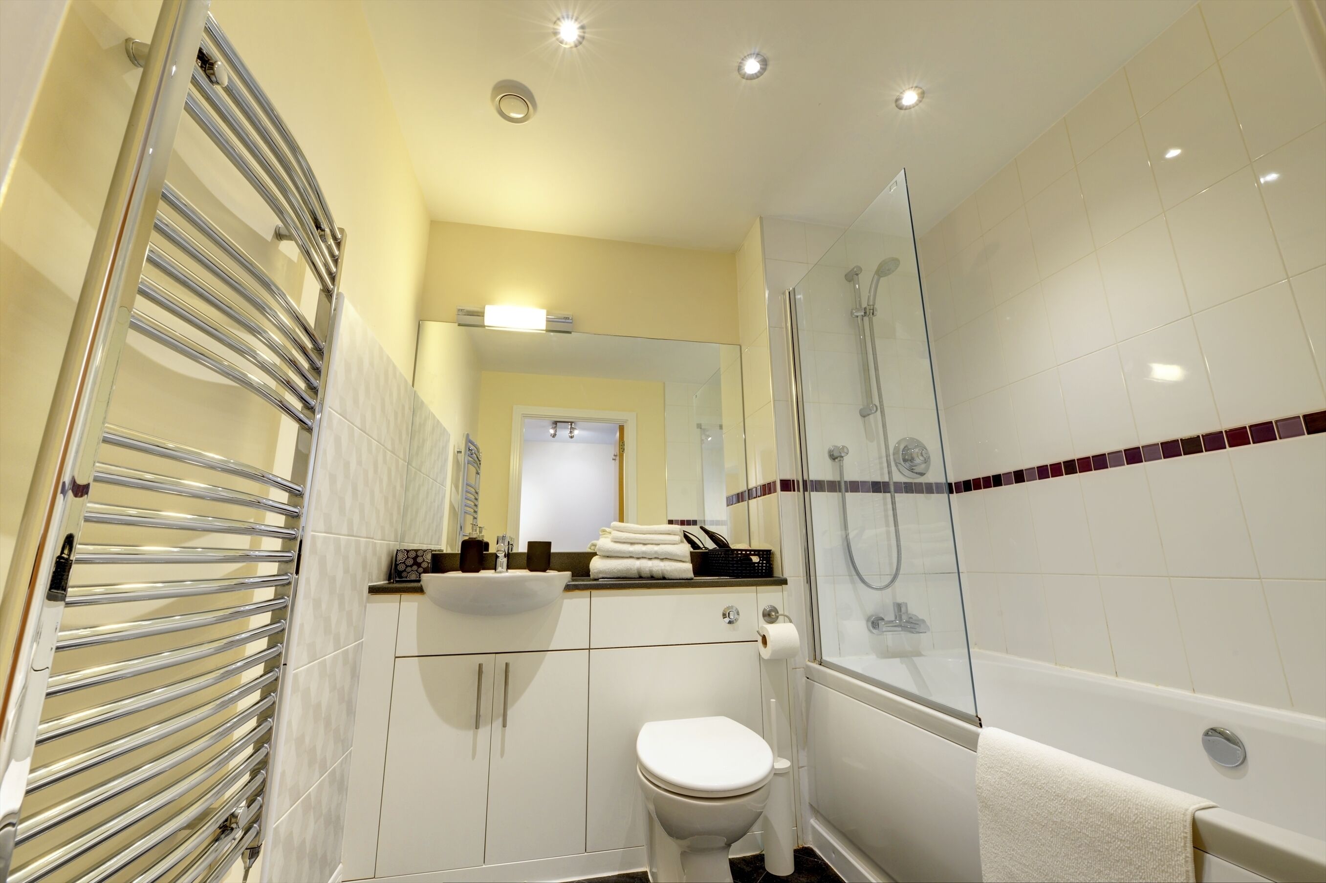 A modern bathroom with a glass shower enclosure, a white toilet, and a built-in sink.