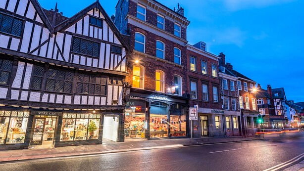 Una strada con edifici tradizionali a graticcio, una banca Lloyds e un Pizza Hut.