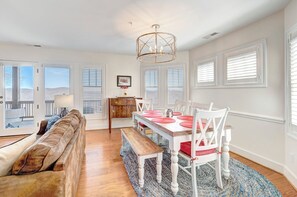 A spacious dining area with a wooden table and chairs, a bench, and a chandelier.