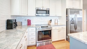 A modern kitchen with white cabinets, stainless steel appliances, and a marble countertop. - Wintergreens R322- Mtn Condo/View, Gated Resort, Indoor/Outdoor Pools & Hot Tub (Banner Elk)