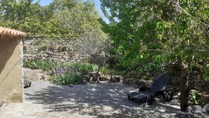 Un espace extérieur rustique agrémenté de murs en pierre, d’un banc en bois et d’une petite table.