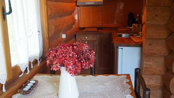 Een gezellig cabin interieur met een houten eettafel, een vaas met rode bloemen en een keuken met houten kastjes en een spoelbak.