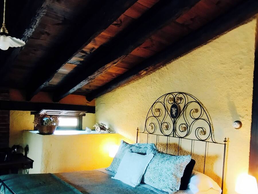 Una camera da letto con un letto, un comodino, una lampada, una finestra e un soffitto in legno.