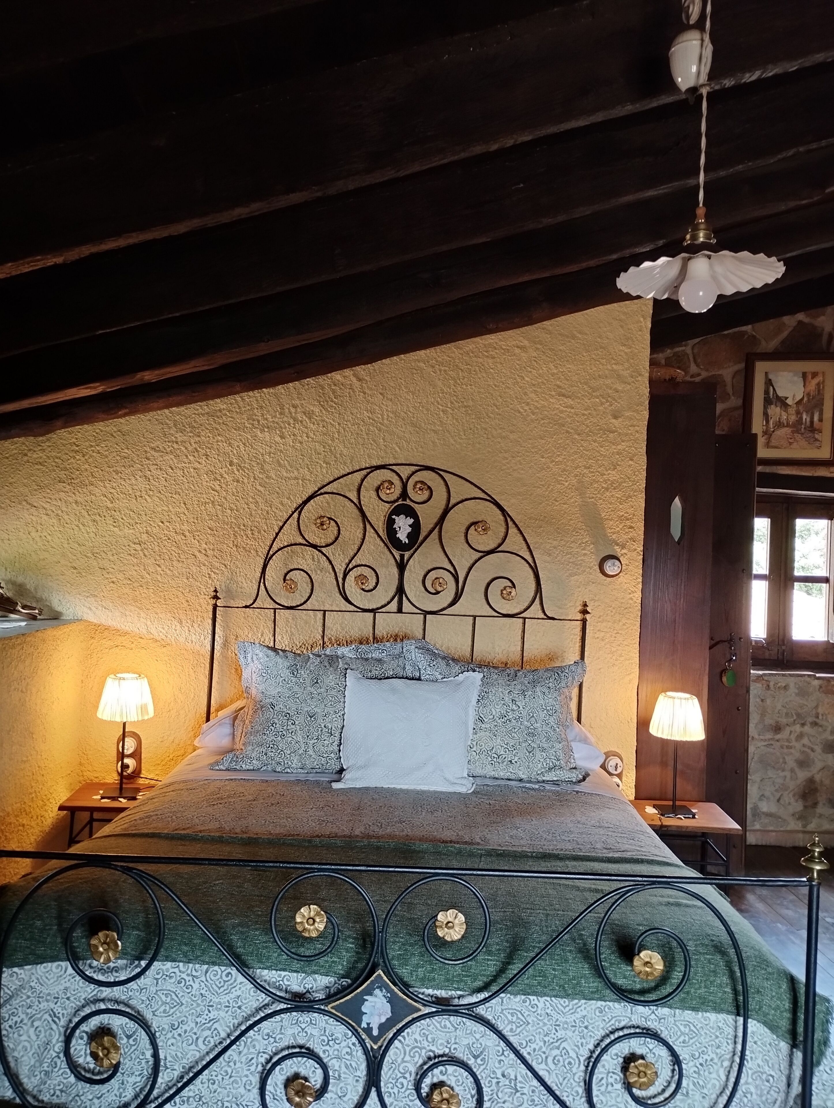 A bed with a decorative headboard, two bedside lamps, and a hanging light fixture.