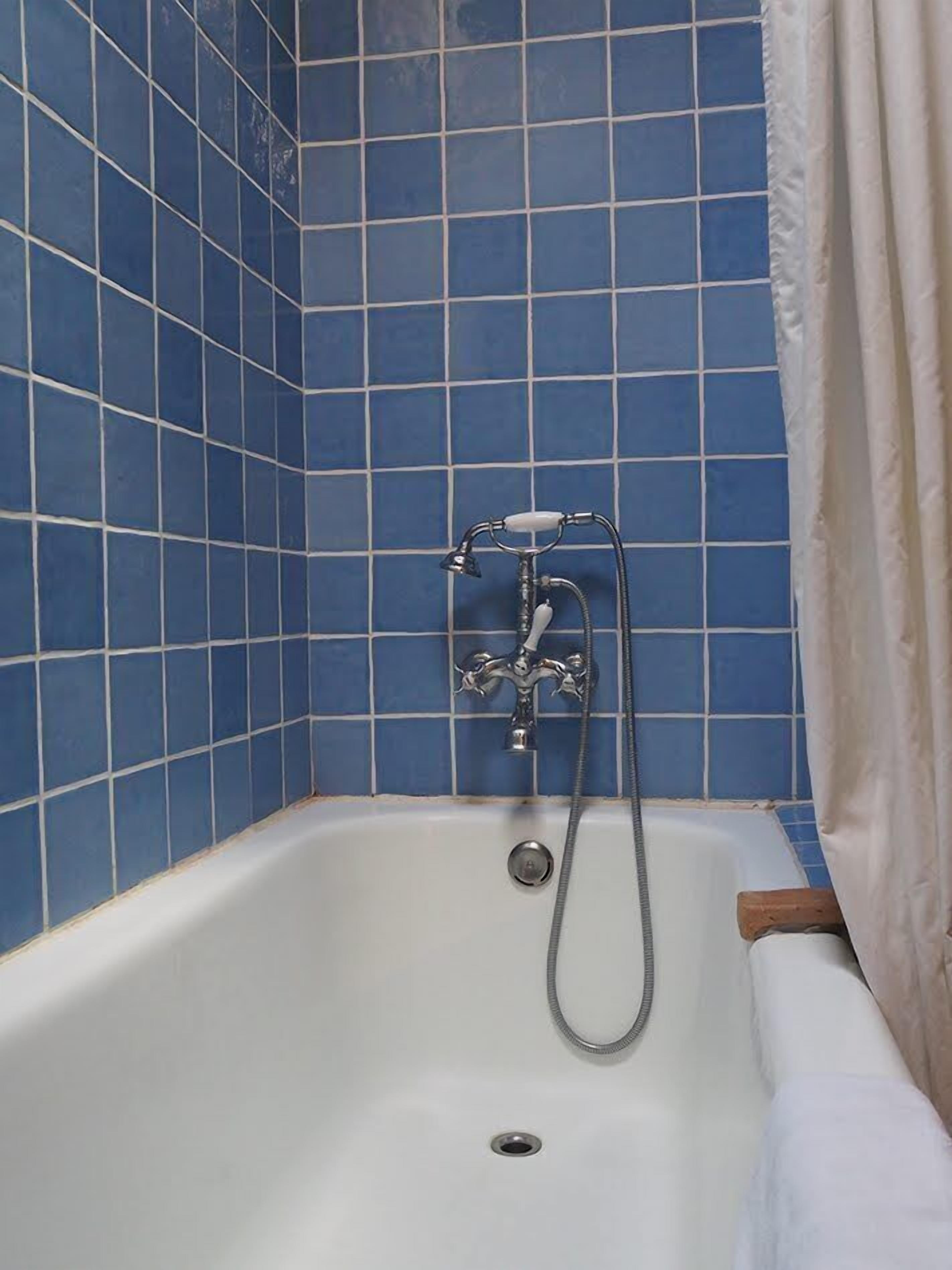 A bathroom with a bathtub, a showerhead, and a curtain.