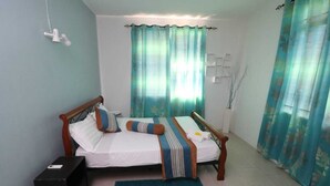 A double bed with a wooden frame, two pillows, a striped blanket, and a blue rug. There is a small black box on the floor to the left of the bed. - Isola Bella Luxury Villa (La Gaulette)