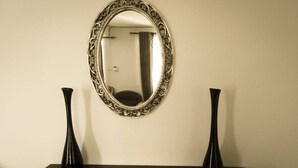 A mirror with an ornate frame on a wall, flanked by two black vases on a dark table. - Isola Bella Luxury Villa (La Gaulette)