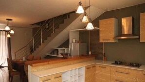 A modern kitchen with wooden cabinets, a central island, and pendant lighting. - Isola Bella Luxury Villa (La Gaulette)